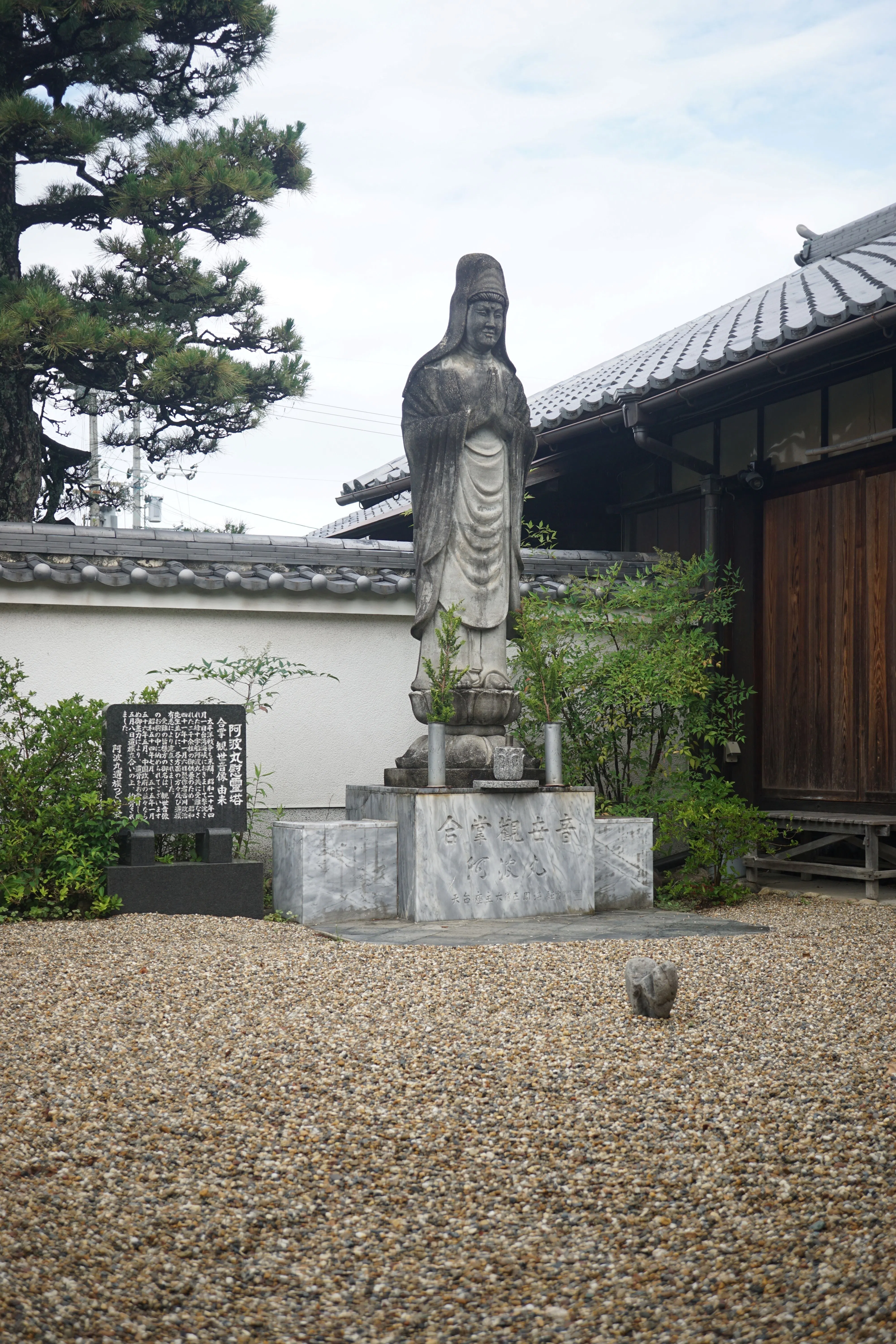 A statue of Kannon stands serenely on a carved stone lotus pedestal.