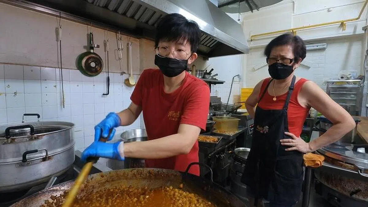 《阿嫲口味的咖喱角》郑美兰（左）与母亲胡秀卿在厨房制作馅料。（图片由新传媒提供）