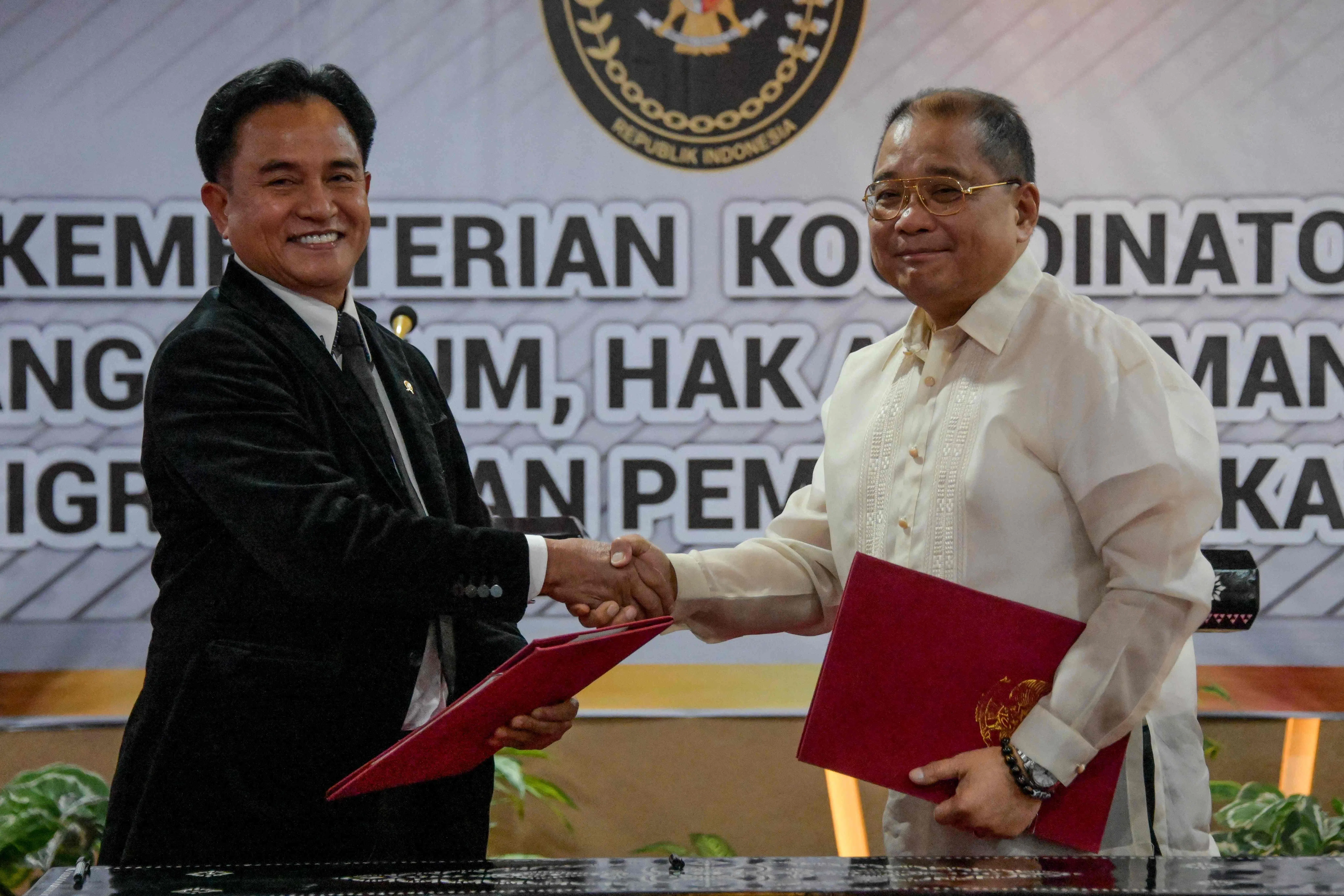 印尼法律事务、人权、移民与惩教事务统筹部长尤斯里（左）和菲律宾司法部副部长巴斯克斯，12月6日在雅加达就遣返死刑犯维罗索的计划交换签署文件。（法新社）