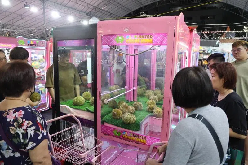 放有小猫山王的榴梿机吸引不少人目光，大家围观看新手和高手如何抓出榴梿。（吴伟国摄）