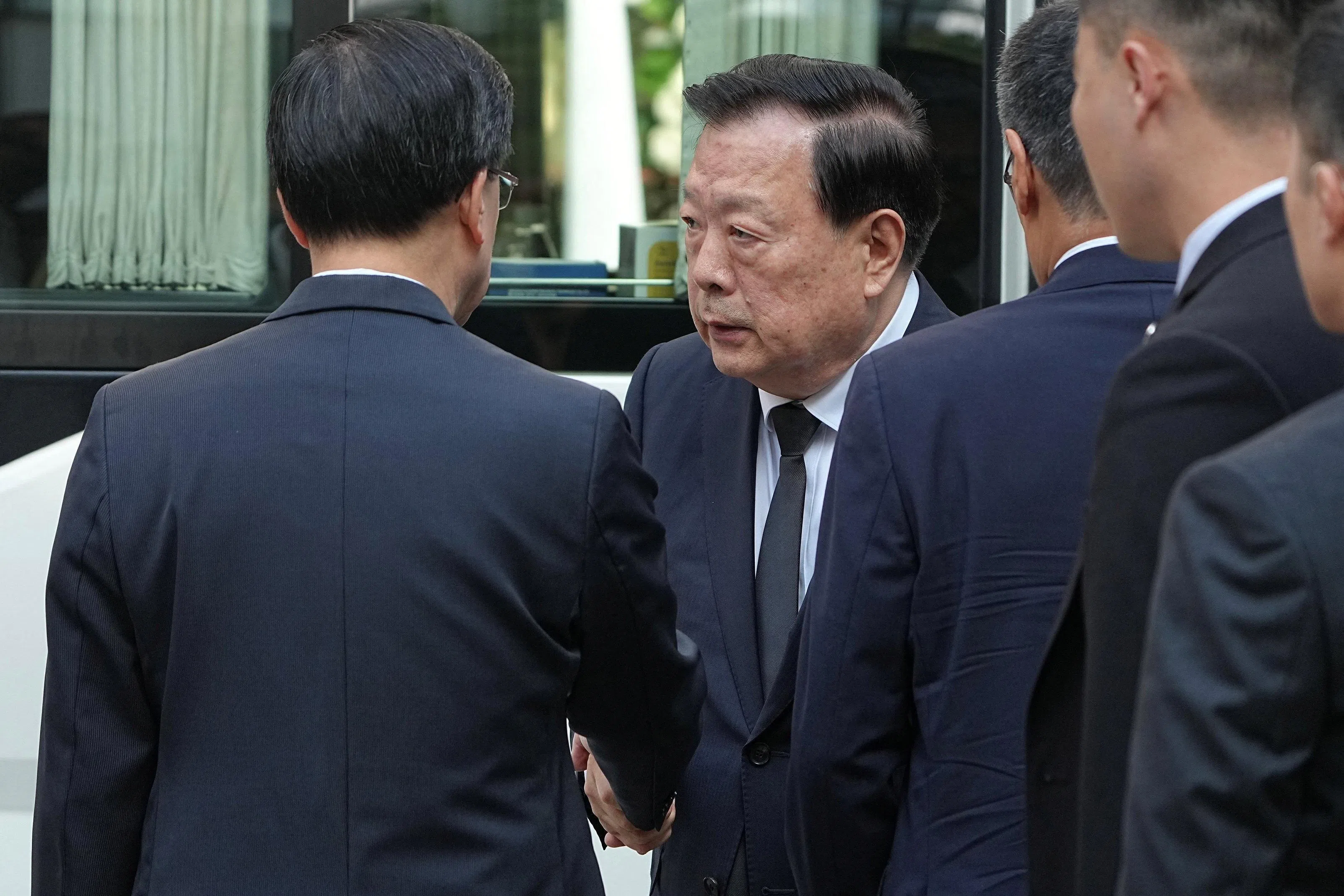 香港首任特首董建华9月8日逝世，公祭仪式星期天（9月20日）以国葬规格在香港举行。港澳办主任夏宝龙（左二）出席公祭仪式，在现场与香港特首李家超（左一背对着镜头者）握手致意。（路透社）