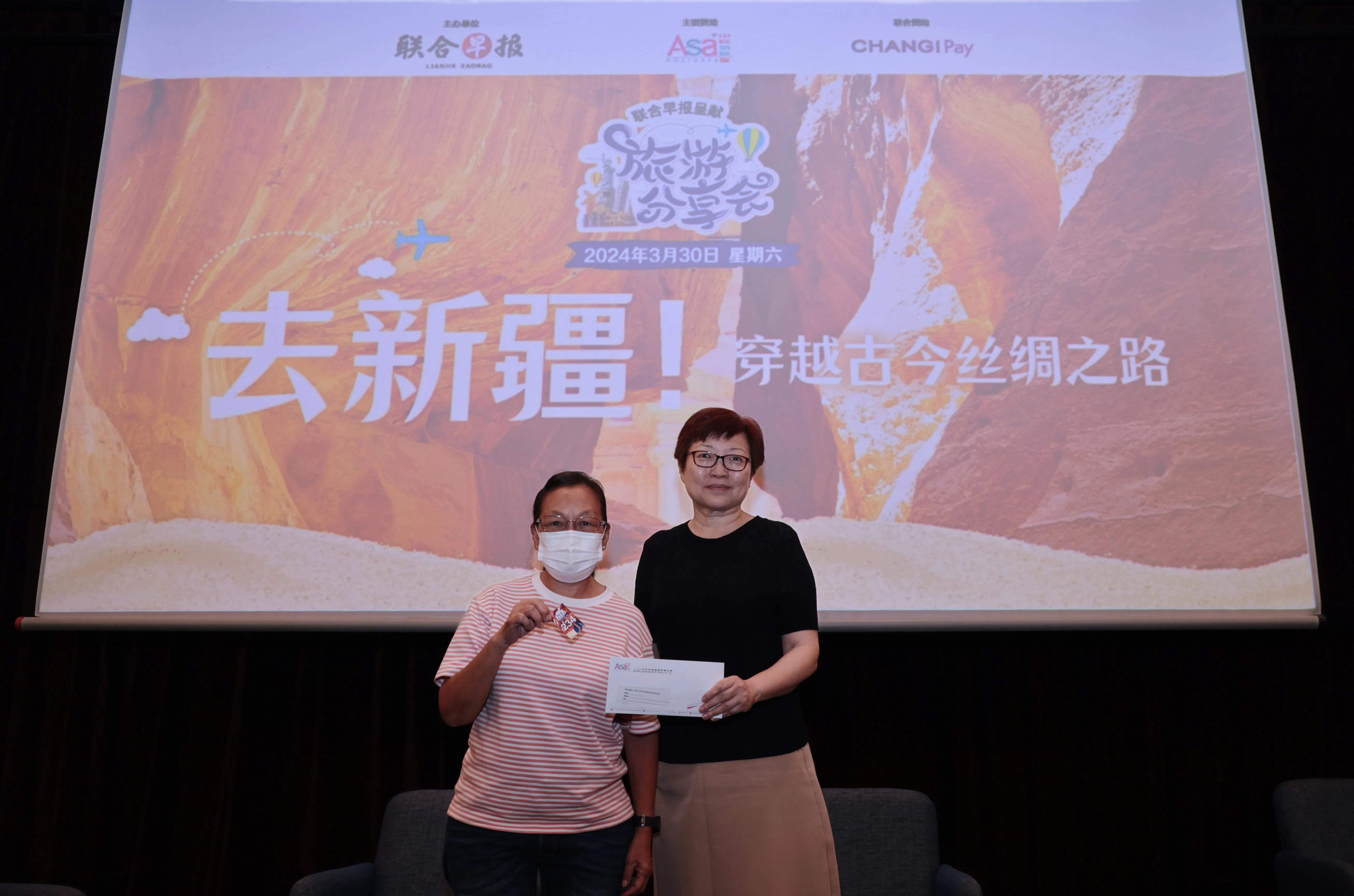 旅游分享会上一名幸运儿从中欧航旅高级策划经理吴雯（右）手中领取一对来回汕头的机票。（梁麒麟摄）