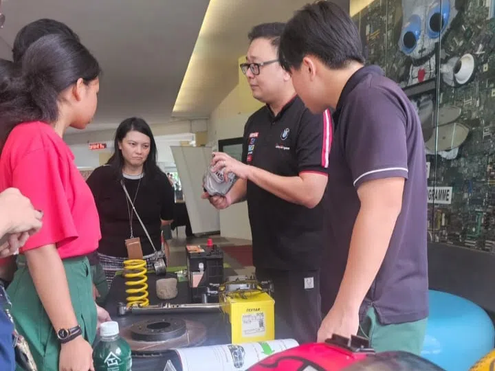 赛车俱乐部的代表向学生解说赛车的各种零件。（丰嘉中学提供）