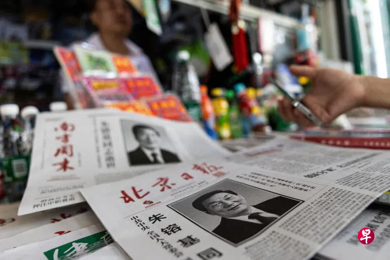 在中国首都北京，一名男子星期四（8月13日）在报摊购买商品，摊上陈列着刊登中国前总理朱镕基讣告的报纸。朱镕基在星期三（8月12日）逝世。 （路透社）