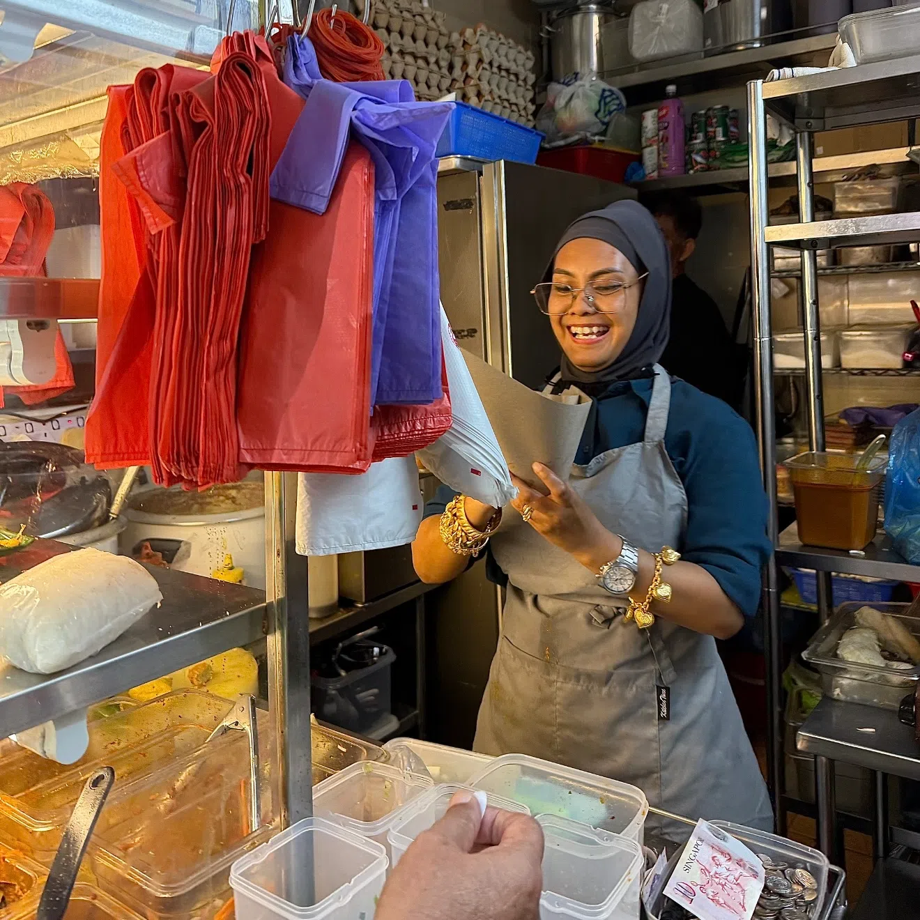 即便在闷热的摊位上工作超过10小时，哈妮依然面带微笑服务食客。（萧康达摄）