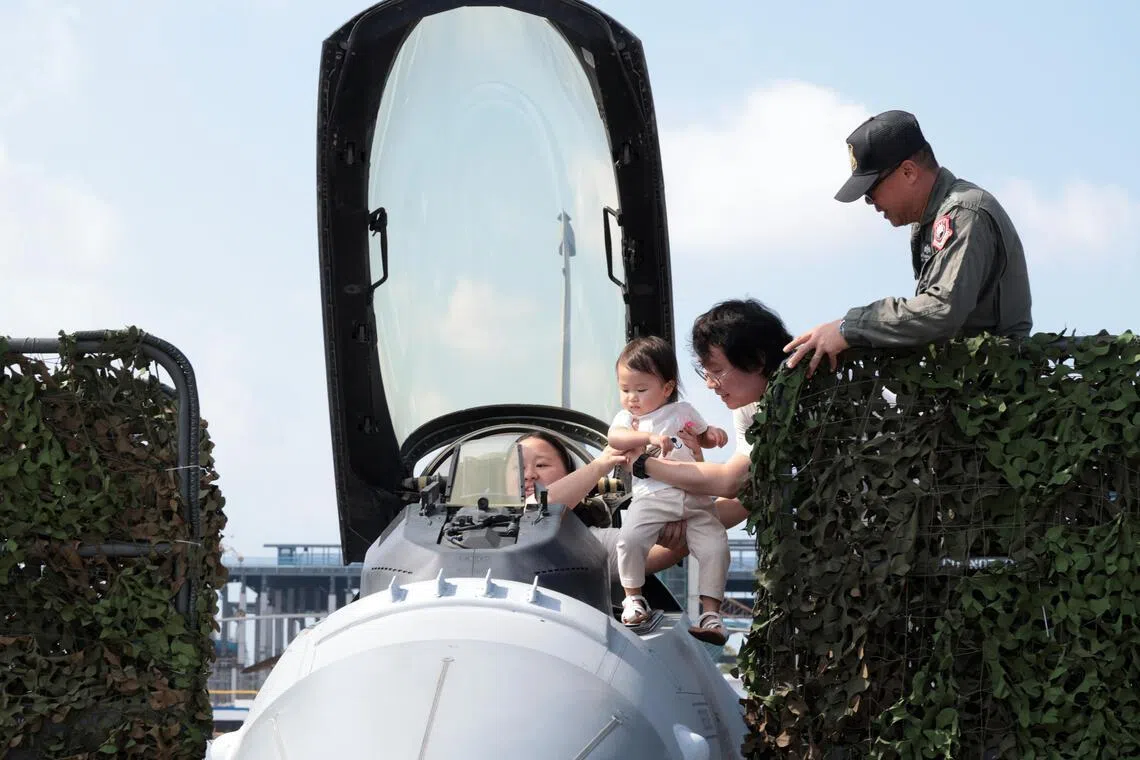 新加坡航空展吸引不少家庭到场参观，有父母抱着婴儿登上展示战机机舱体验，从驾驶员视角拍照留念。（邝启聪摄）