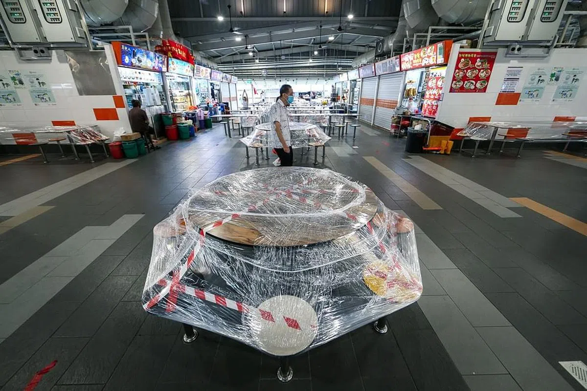 2020年冠病阻断措施期间，芽笼峇鲁小贩中心内的餐桌椅都用塑料膜包起，以免有人坐下用餐。（叶振忠摄）