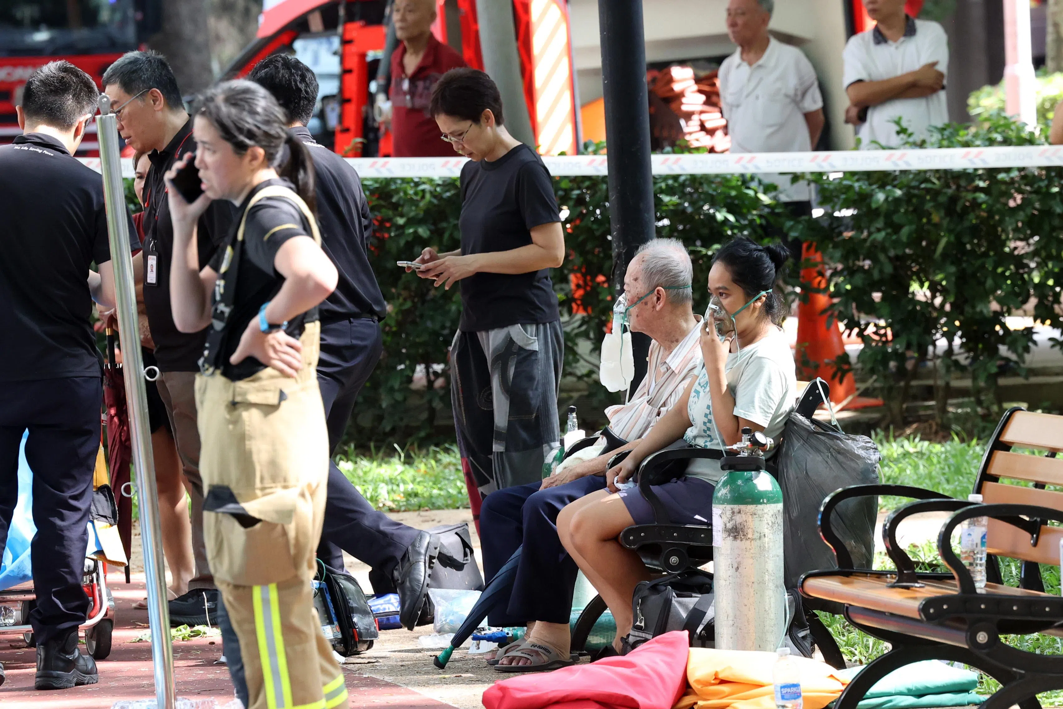 火患发生后，几名感到不适的居民在组屋楼下的球场吸氧并接受医护人员的检查。（邝启聪摄）