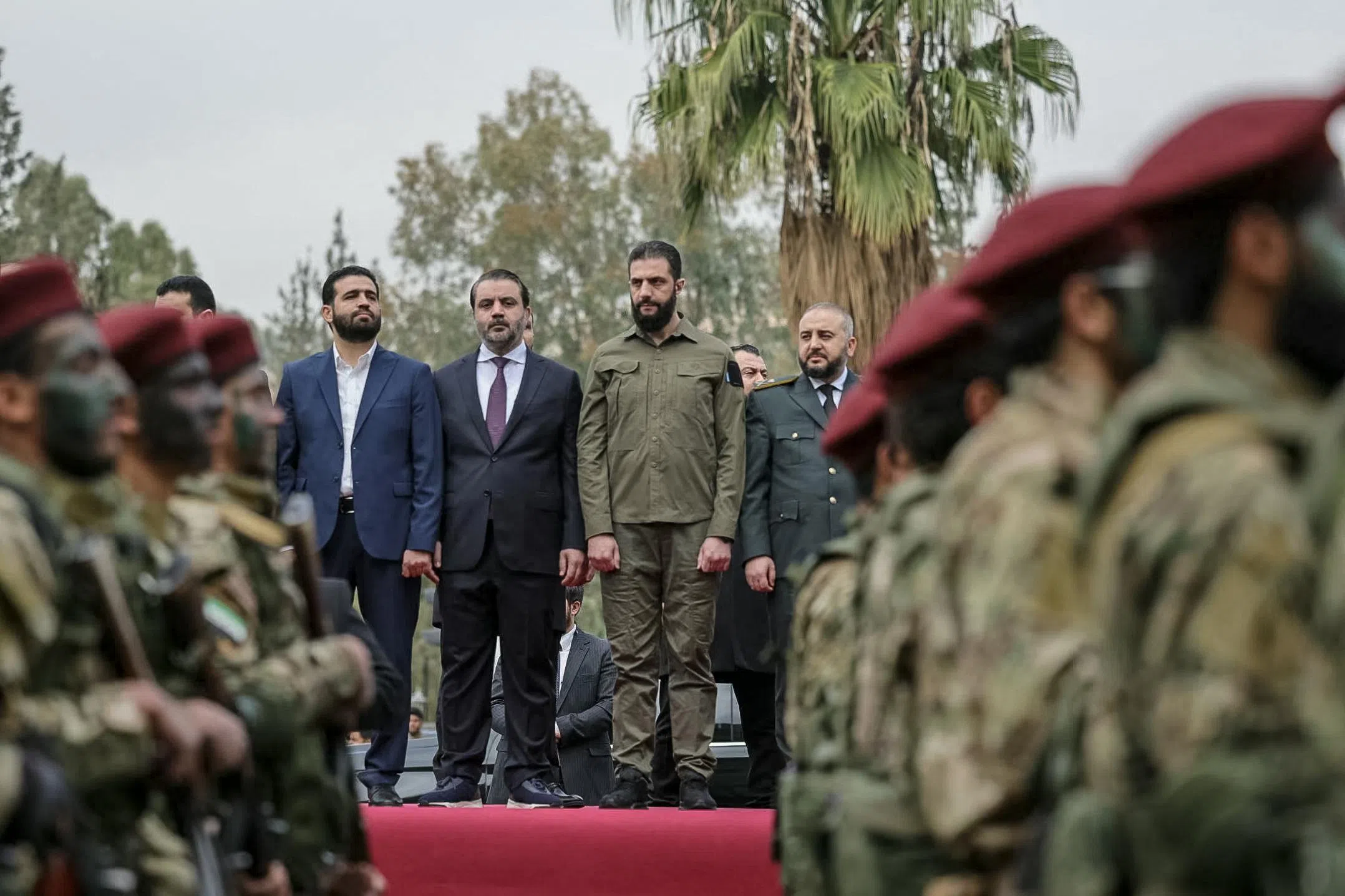 叙利亚过渡总统沙拉（红毯右二）12月8日在大马士革检阅军队。（法新社）