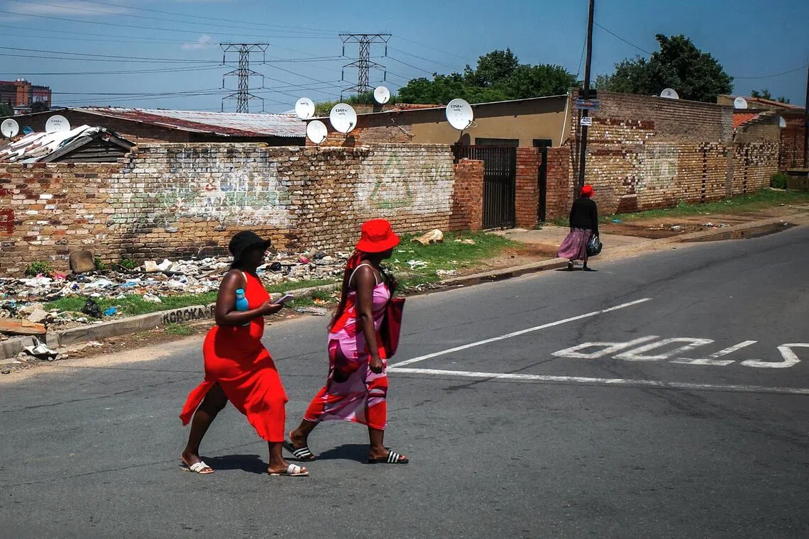 在铁皮与砖墙构成的暗淡背景中，一抹跃动的红色，如生命之火，格外耀眼。（叶振忠摄）