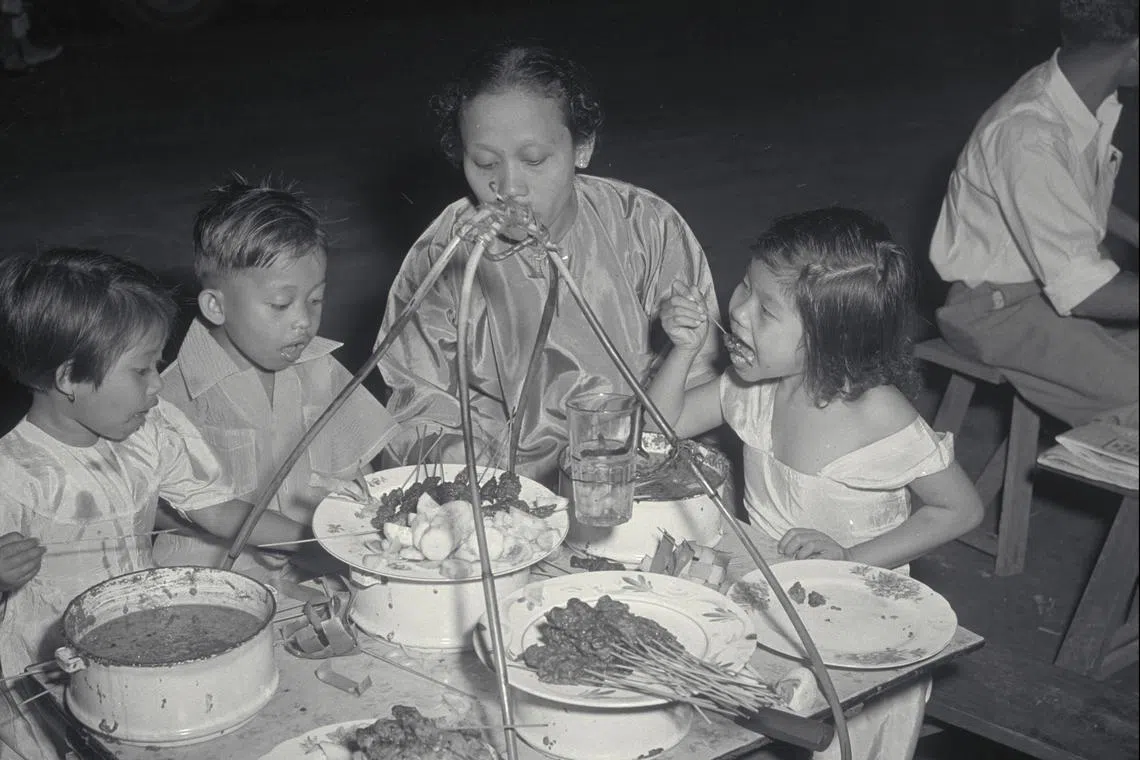 夜晚在路边摊的矮桌椅品尝沙爹。好不好吃？小朋友的表情给了答案。（档案照）