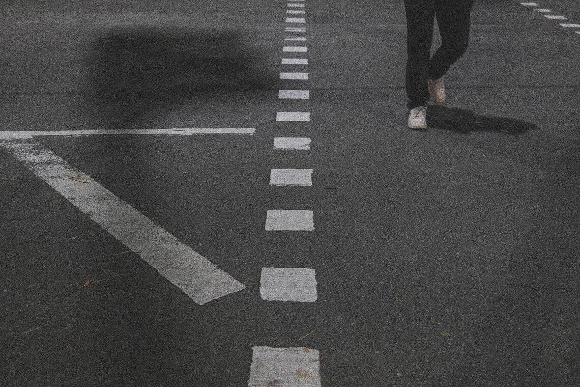 路口灯影与行人身影交汇。（陈渊庄摄）
