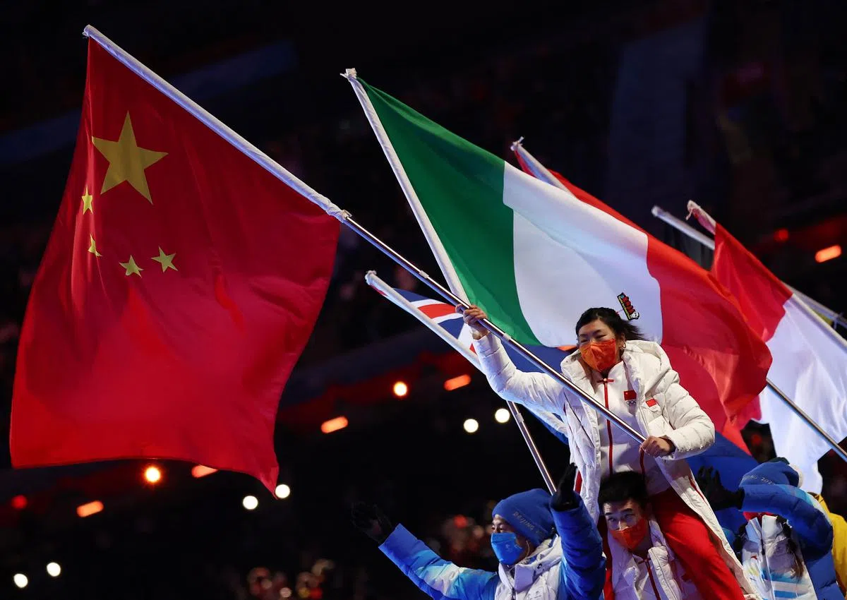 中国代表团旗手徐梦桃挥动着国旗，另一名旗手高亭宇则扛着徐梦桃。（路透社）