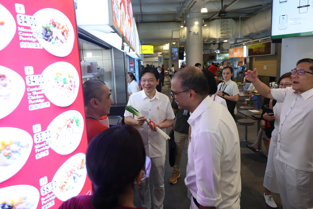 黄循财总理（左二）星期二到榜鹅综合社区中心（One Punggol）小贩中心，为包括原议员普杰立医生（右二）在内的行动党榜鹅团队助阵。一名摊贩赠与黄总理长蒜，代表“冻蒜”，用谐音预祝他“当选”。（白艳琳摄）