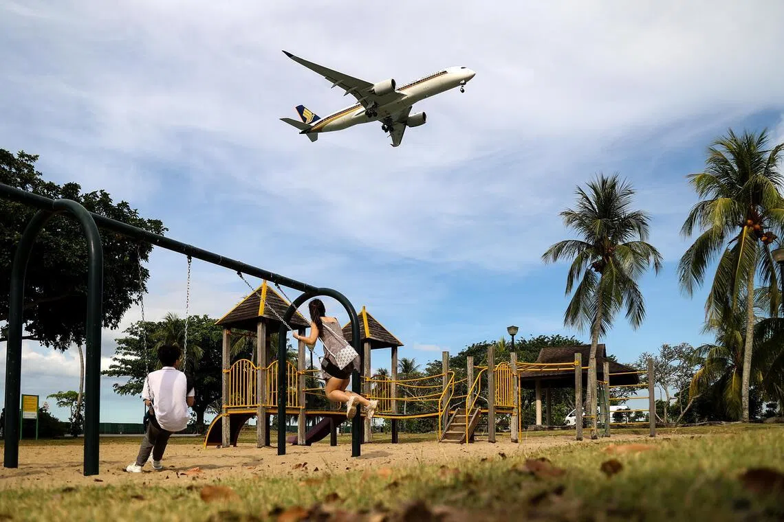 游乐场一隅，秋千上的情侣看着飞机从头顶飞过，仿佛望见远方的幸福。（关俊威摄）