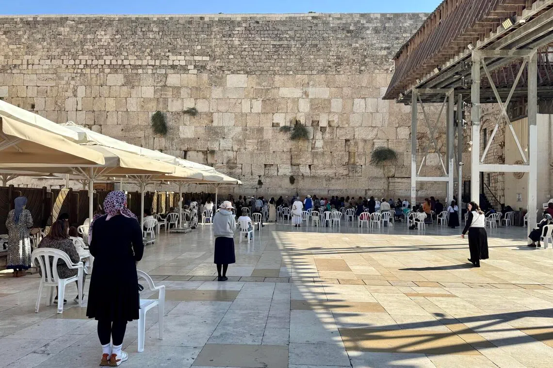 哭墙前的信徒微微摇晃着身体祷告，无视自由进出的游客摄影和摄像。（何惜薇摄）