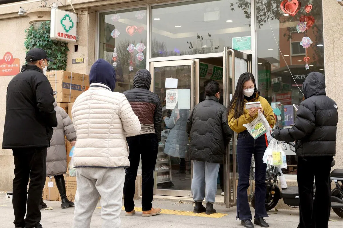 在北京市一个药房外，多名民众星期一（12月12日）在寒冷冬天排队买药。（法新社）