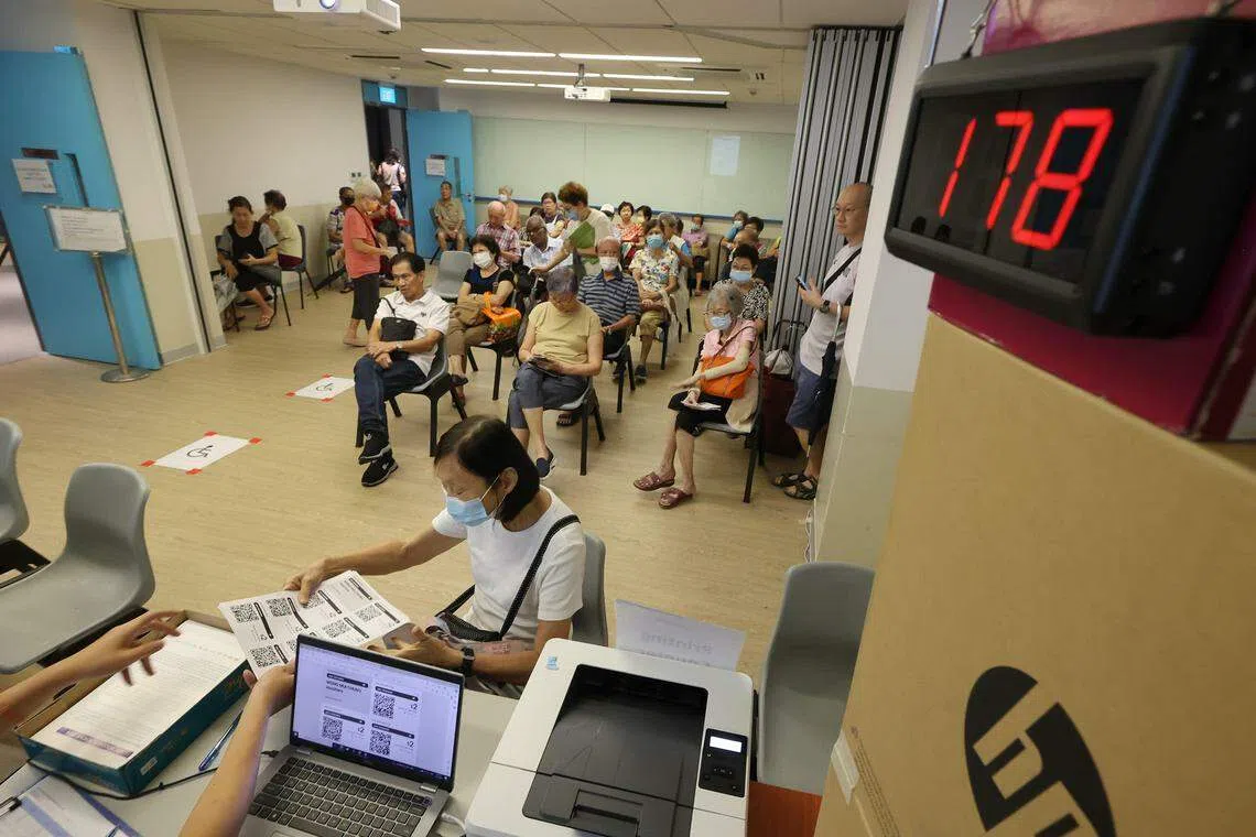 在碧山民众俱乐部，工作人员发出轮候号码，让公众顺利领取纸本购物券。 （唐家鸿摄）