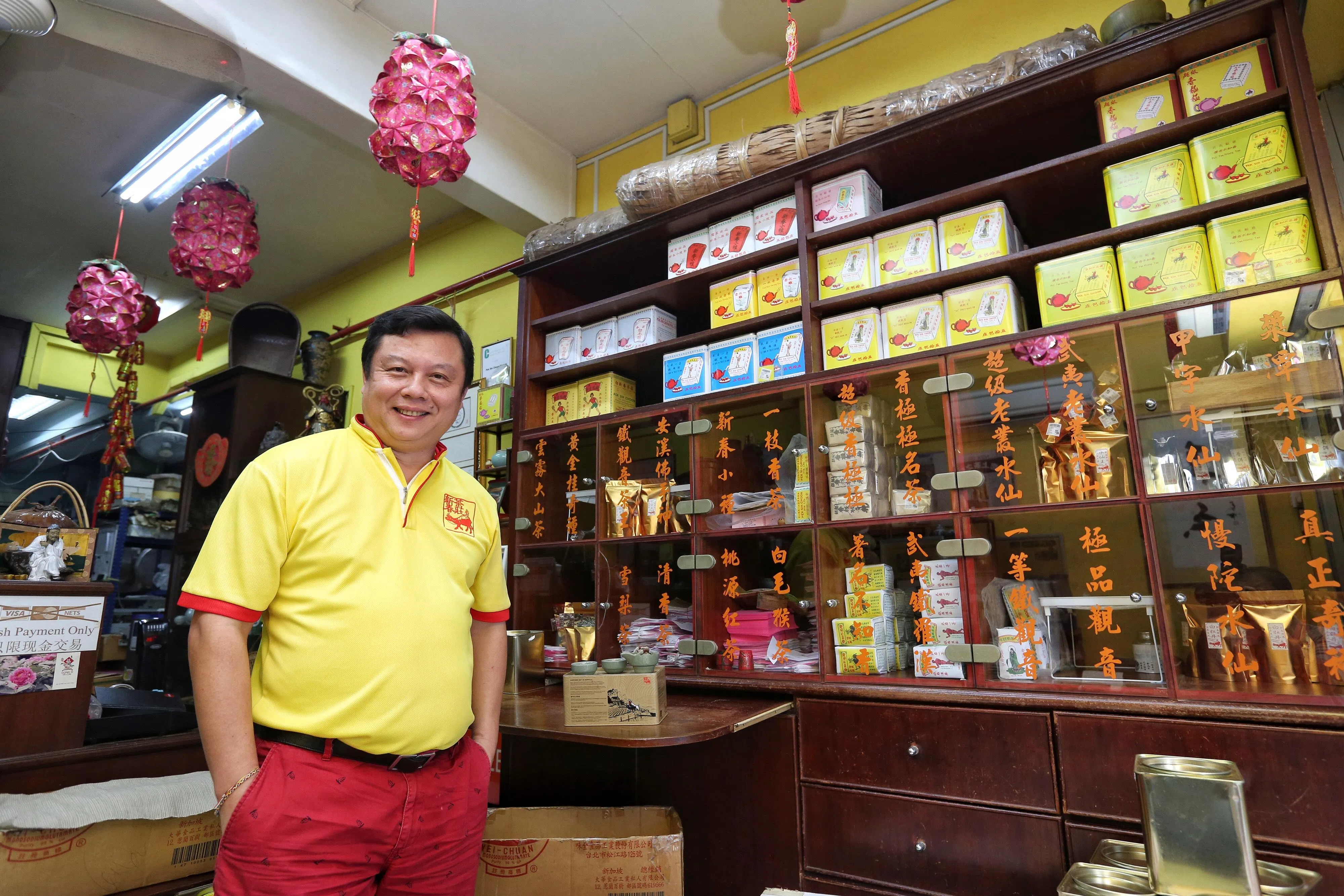 位于牛车水摩士街的白新春茶庄已有98年历史，如今由第四代负责人白进火接管。店内的橱柜内摆放着白新春茶庄在不同时期推出的不同系列茶叶。（陈褔洲摄）