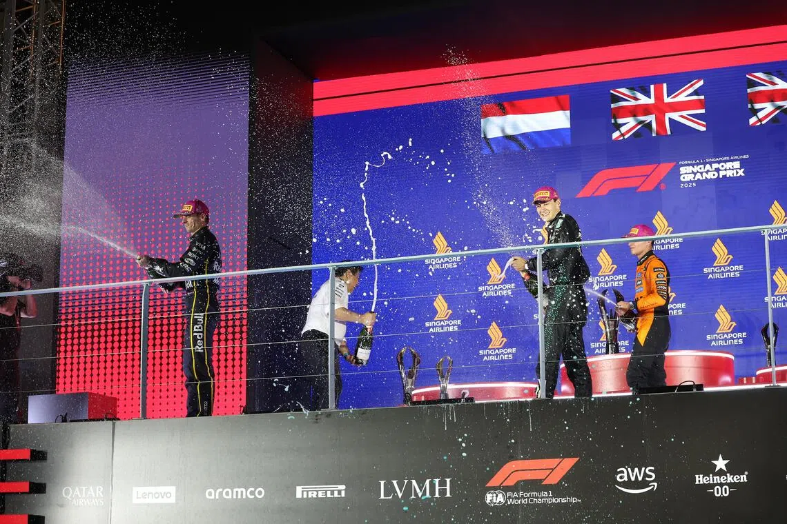 （左起）亚军费斯塔彭、冠军拉塞尔和季军诺里斯将香槟喷向台下同欢。（唐家鸿摄）