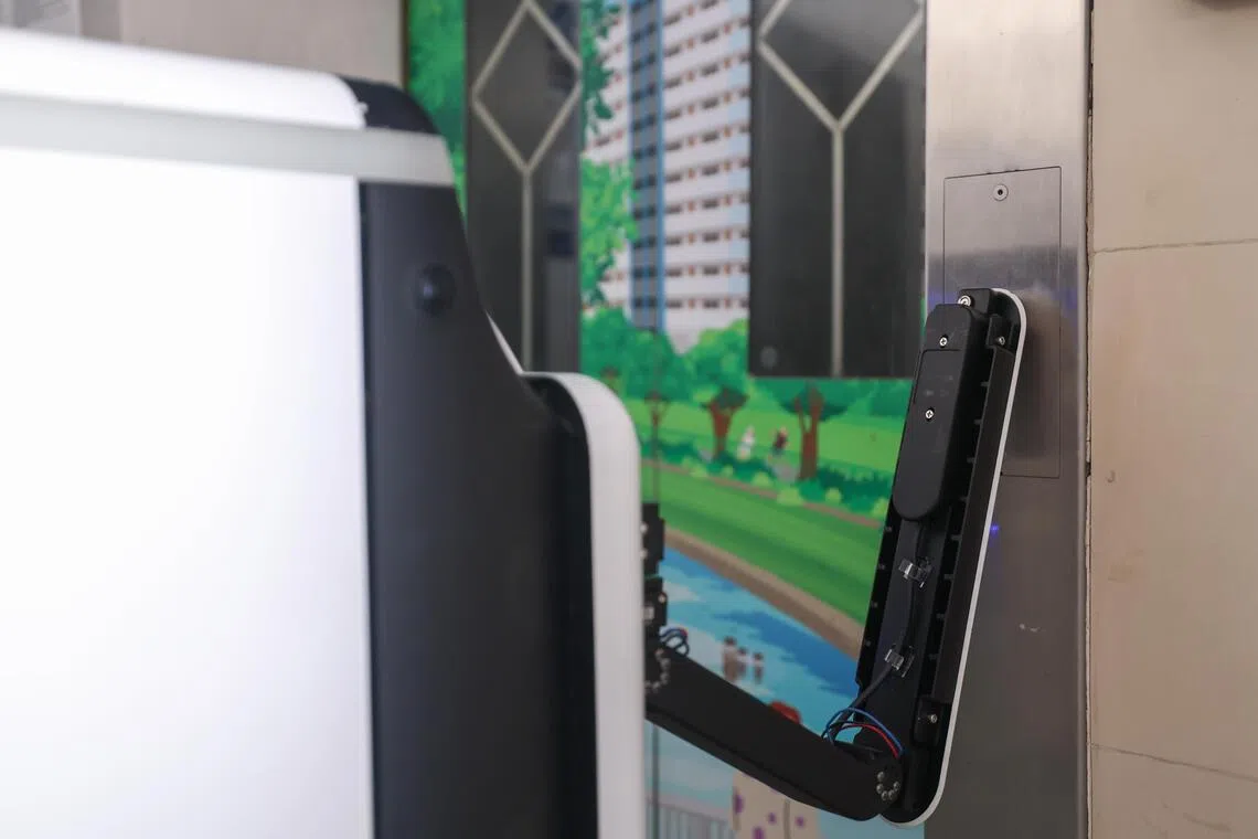 AIDEN机器人会伸出“机械手”自行按电梯键上下楼，以完成送物任务。（白艳琳摄）