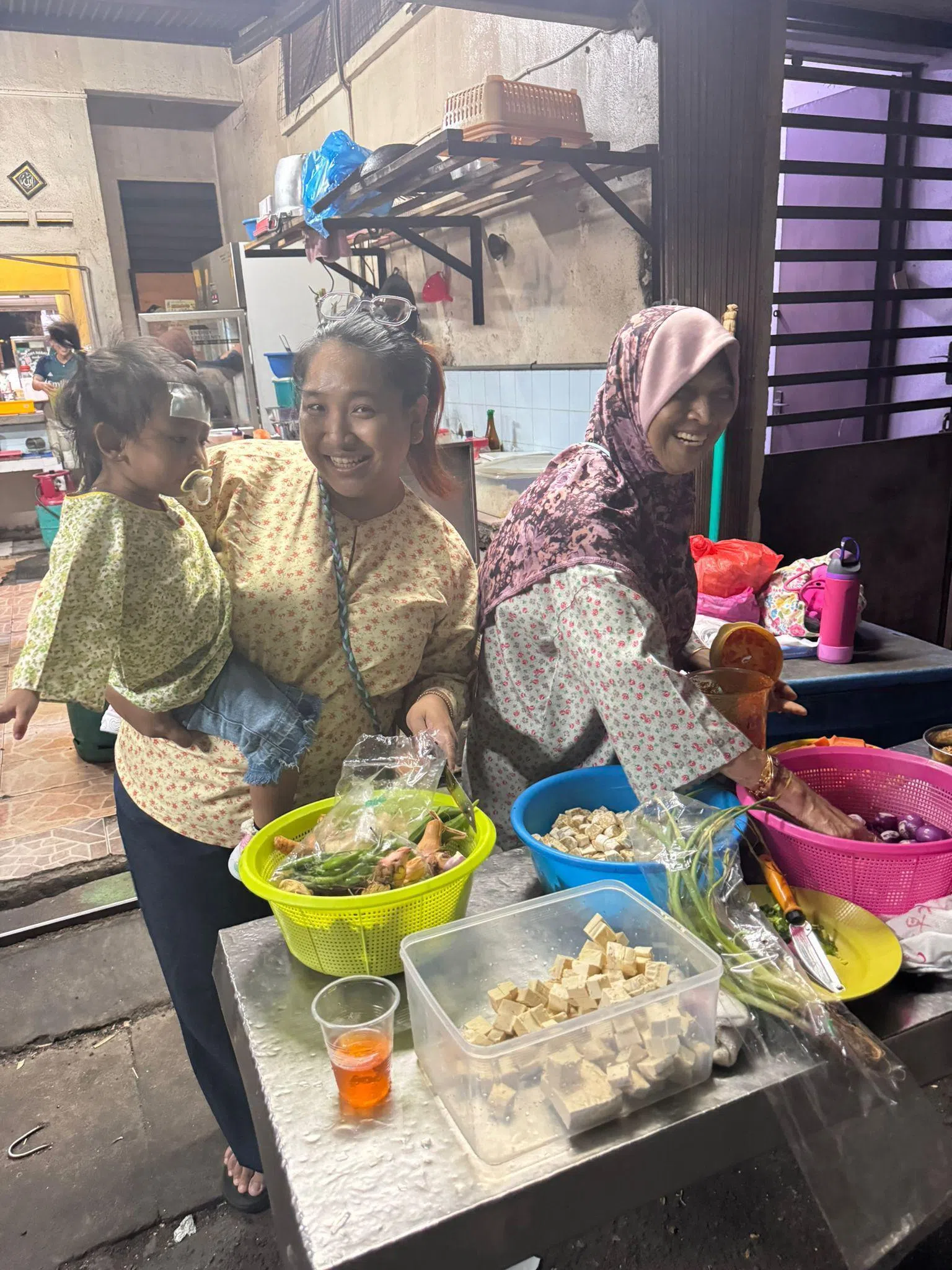 珠爱林的家人，包括母亲诺丽塔（右）和妹妹凯林（中），星期五（20日）在麻坡外祖老家动手准备开斋节的大餐。（受访者提供）