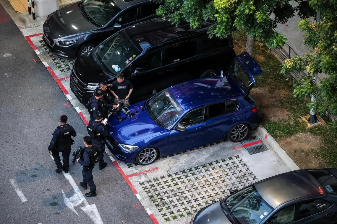 数名警员过后围绕着一辆汽车，一名男子正在一旁接受警员问话。（关俊威摄）