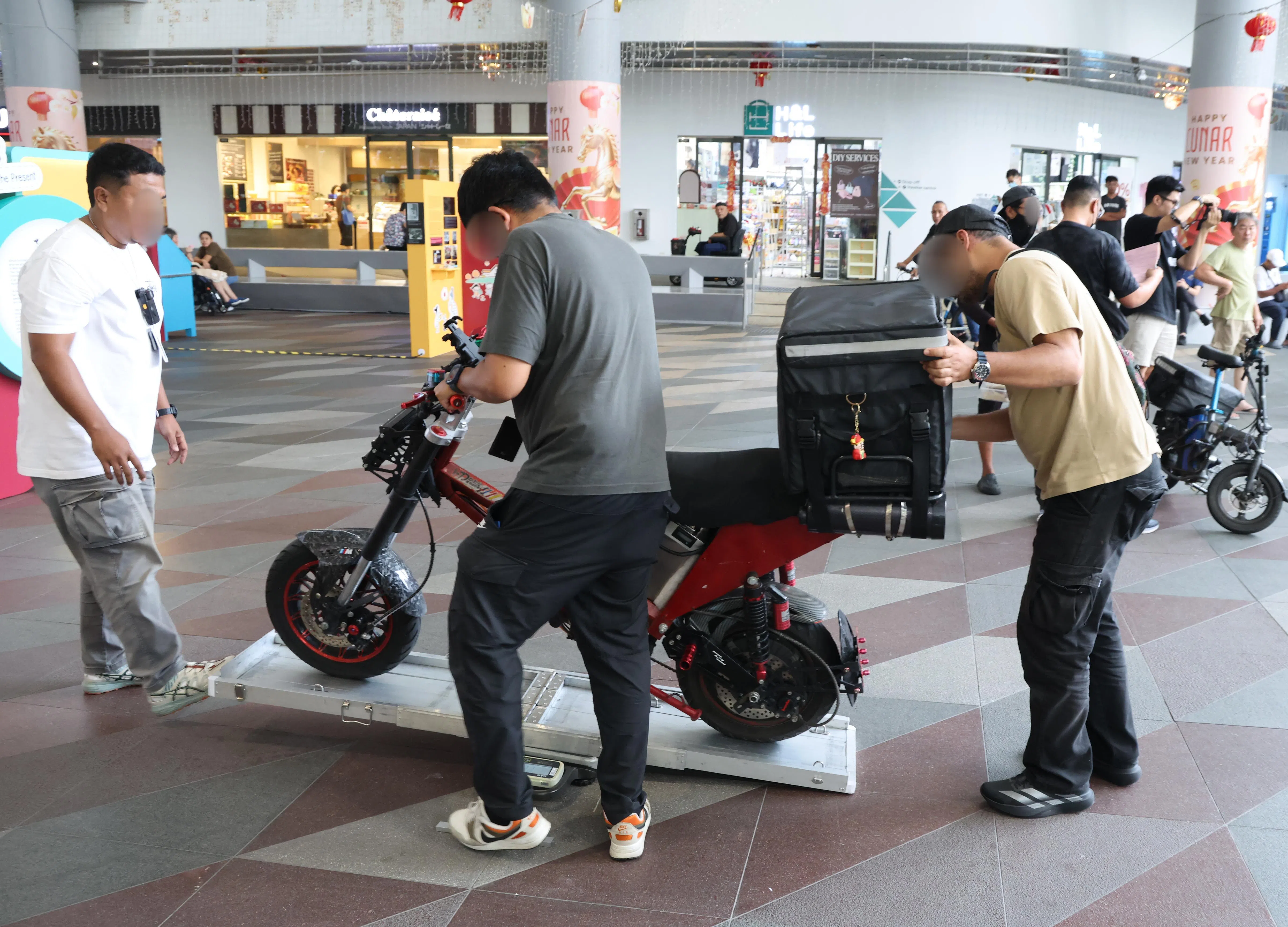 陆交局执法人员在星期一的执法行动中，测量代步工具的重量，检查是否合规。（梁麒麟摄）