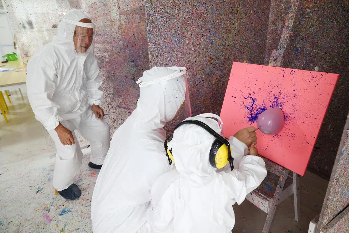 本地画室Art Pop Studio将以自家开创的气球泼墨艺术工作坊项目 ，参与新加坡文化通行证计划。一个扶老携幼的家庭早前参与这个工作坊时，用飞镖刺破装满颜料的气球，在画布上创造色彩斑斓的抽象画作。（蔡家增摄）