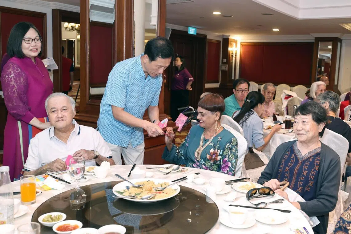 王乙康（左三）在现场给年长者送出红包祝福，左一为福善活跃乐龄中心执行长翁秀卿。（周国威摄）