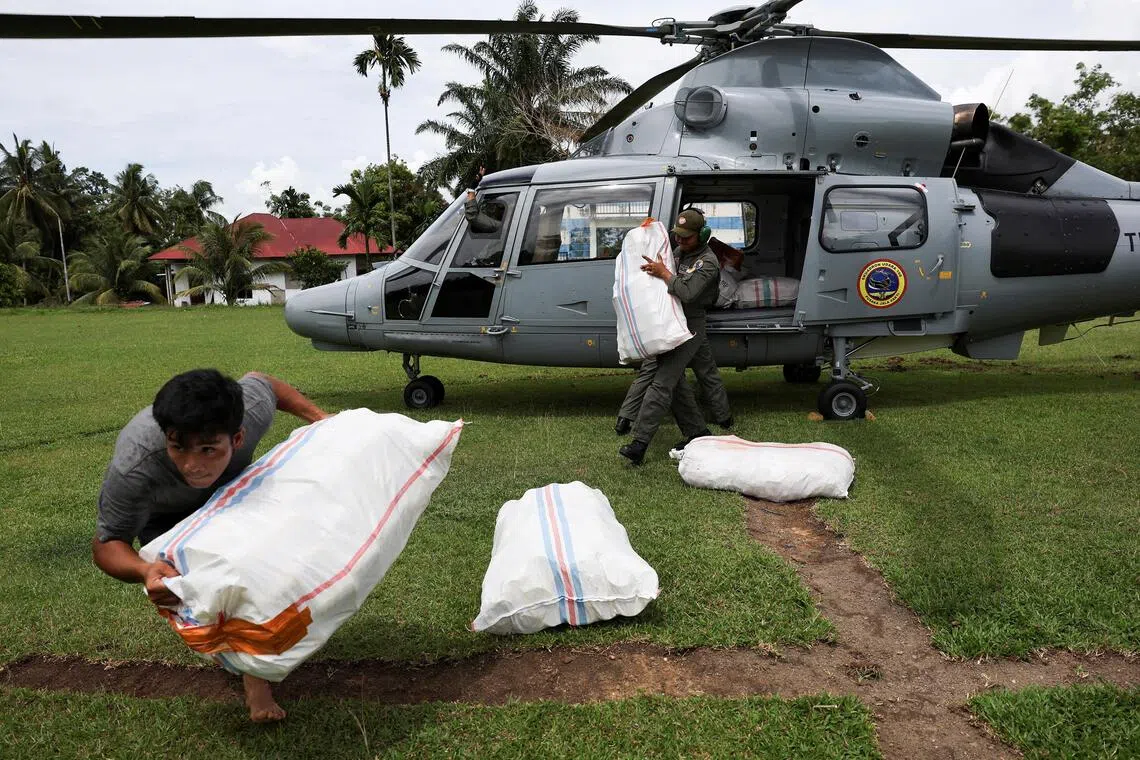 11月30日，西苏门答腊省一名男子协助搬运由印尼海军直升机运来的救援物资。（路透社）
