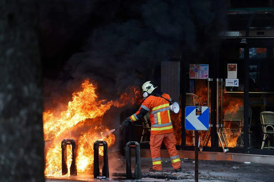 抗议者还点燃脚踏车、建筑物等，图为消防员正在扑灭火势。（法新社）