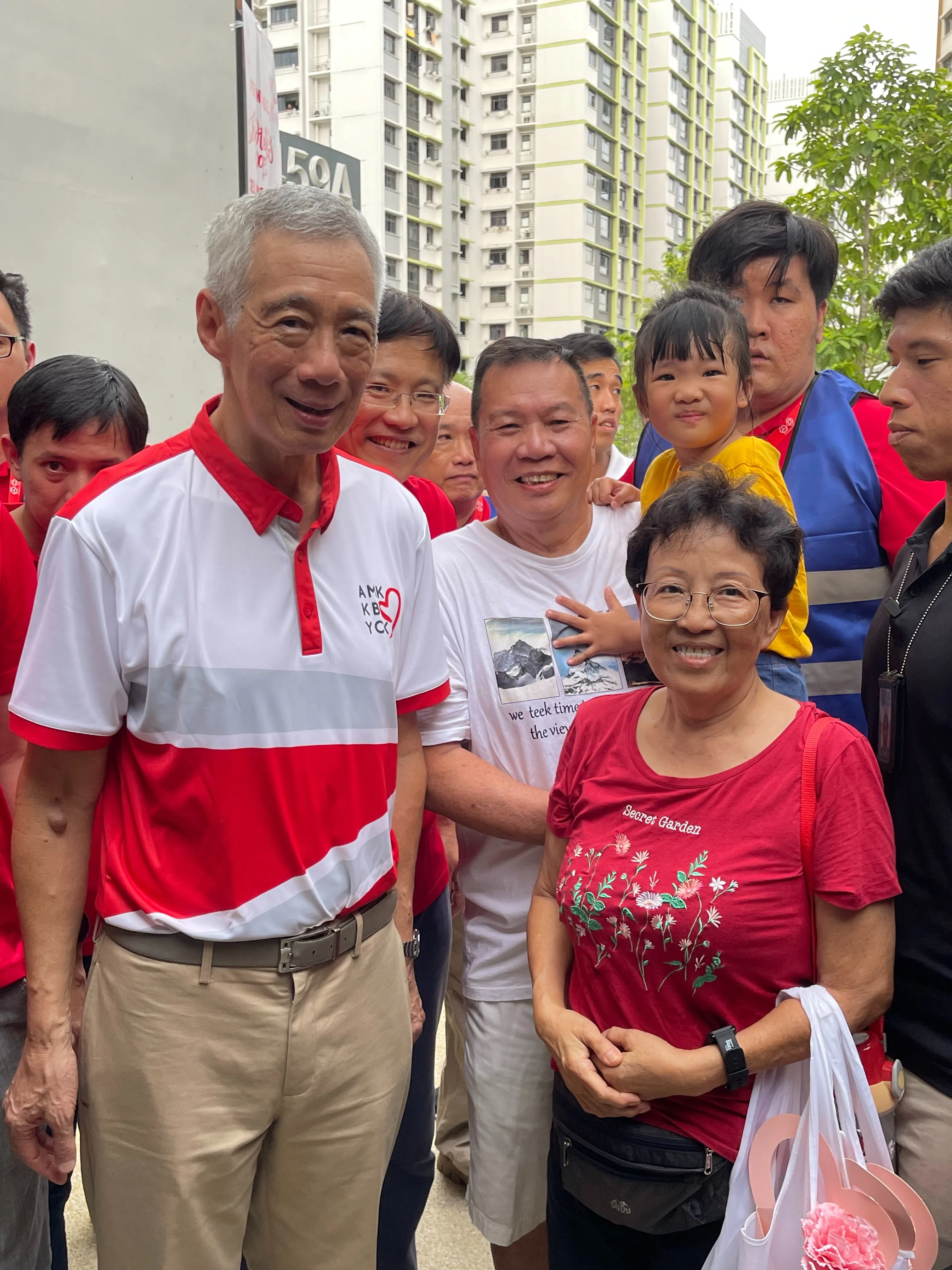 芬维尔区居民吴亚华（中间）和妻子吴玉梅（右一）以及五岁的孙女在人潮中抓住时机，与李总理（左一）和负责芬维尔区事务的宏茂桥集选区议员颜添宝（左二）合照。（受访者提供）