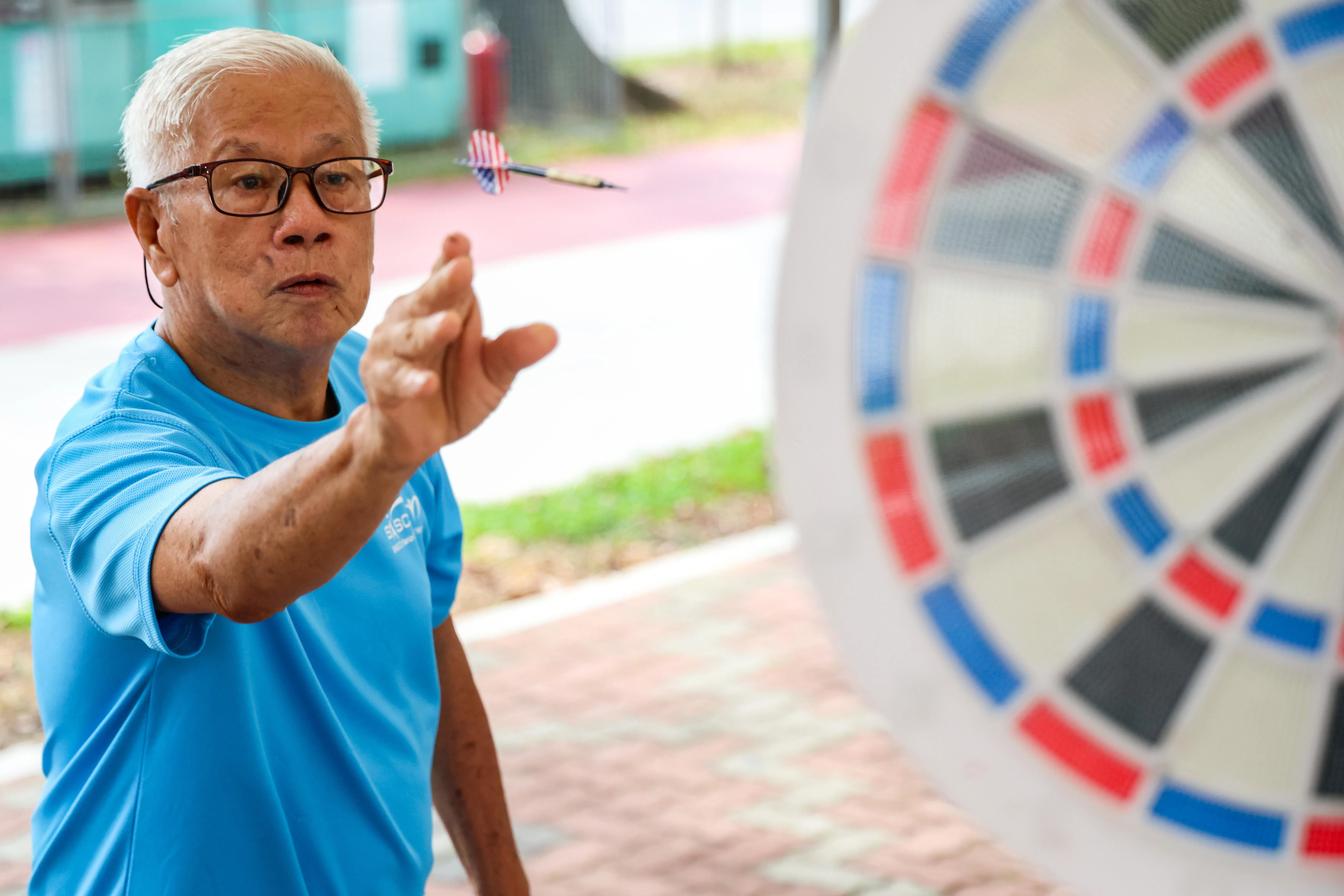 退休人士梁敬全（84岁）去年在萨司歌（SASCO）西海岸活跃乐龄中心工作人员的介绍下，加入兄弟兴趣小组。兄弟兴趣小组定期举办各种活动，包括飞镖游戏。（陈斌勤摄）