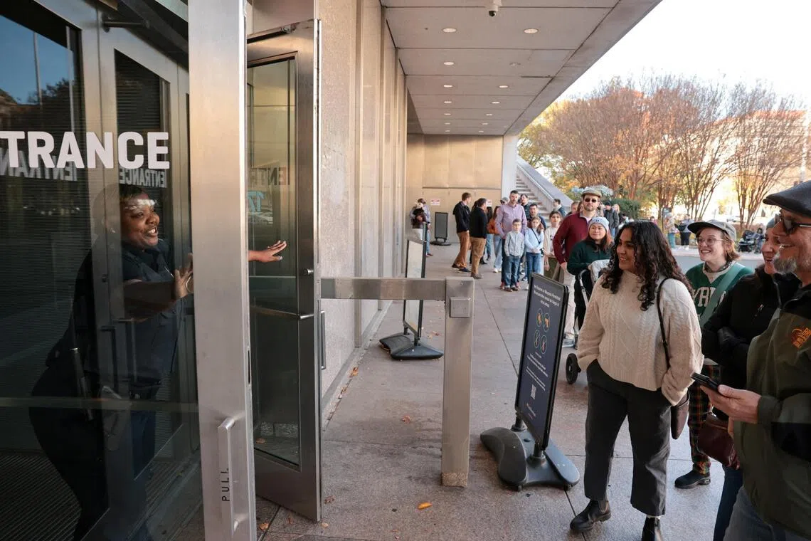 美国国家历史博物馆星期五（11月14日）重新开放，开门的保安微笑迎接在外头兴奋等待的访客。（路透社）