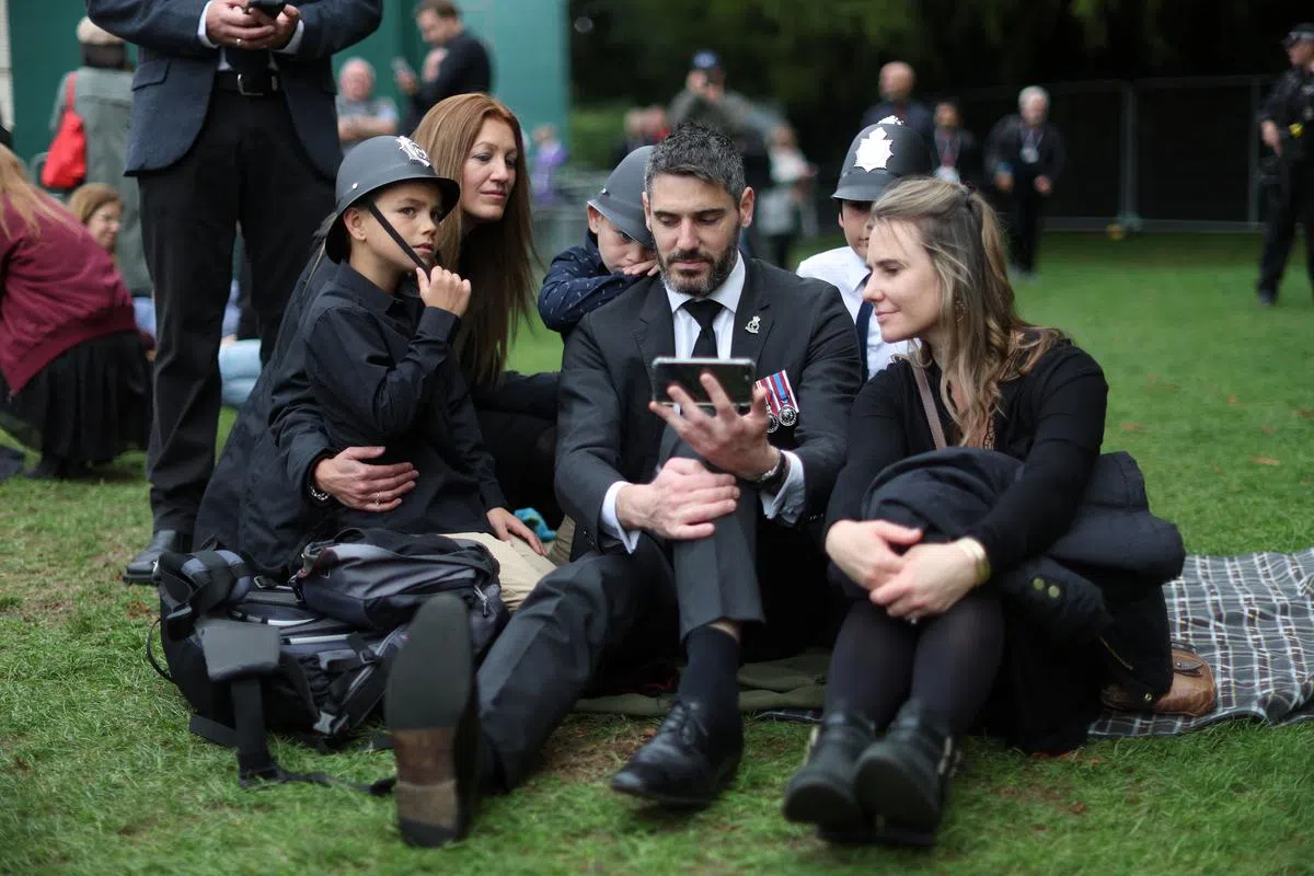 温莎城堡外，民众收看女王国葬直播。（路透社）