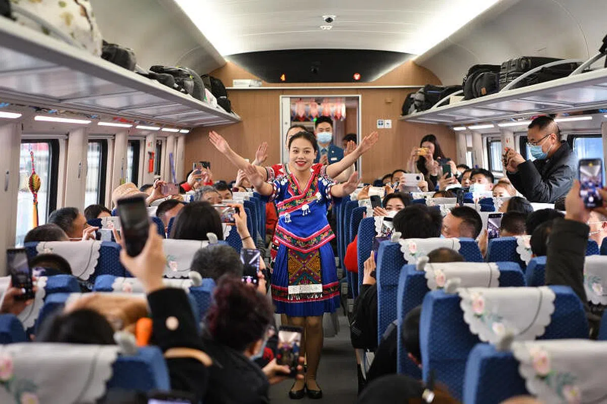 身着民族服饰的列车员为旅客带来特色节目。（中新社）