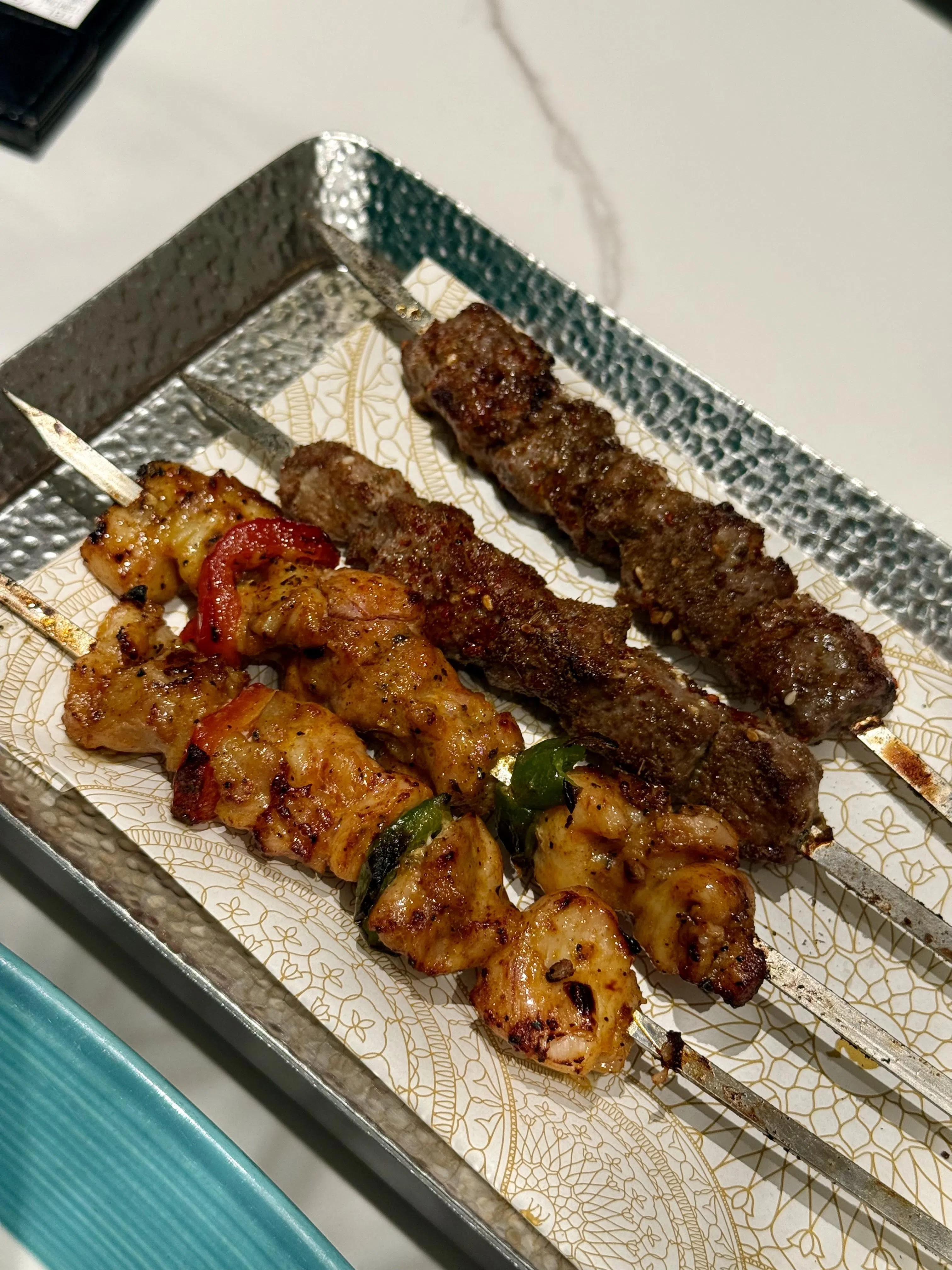 招牌铁签子羊肉串和烧烤鸡肉串烤得外焦里嫩，肉汁丰盈，保留炭火的原始风味。（叶晓虹摄）