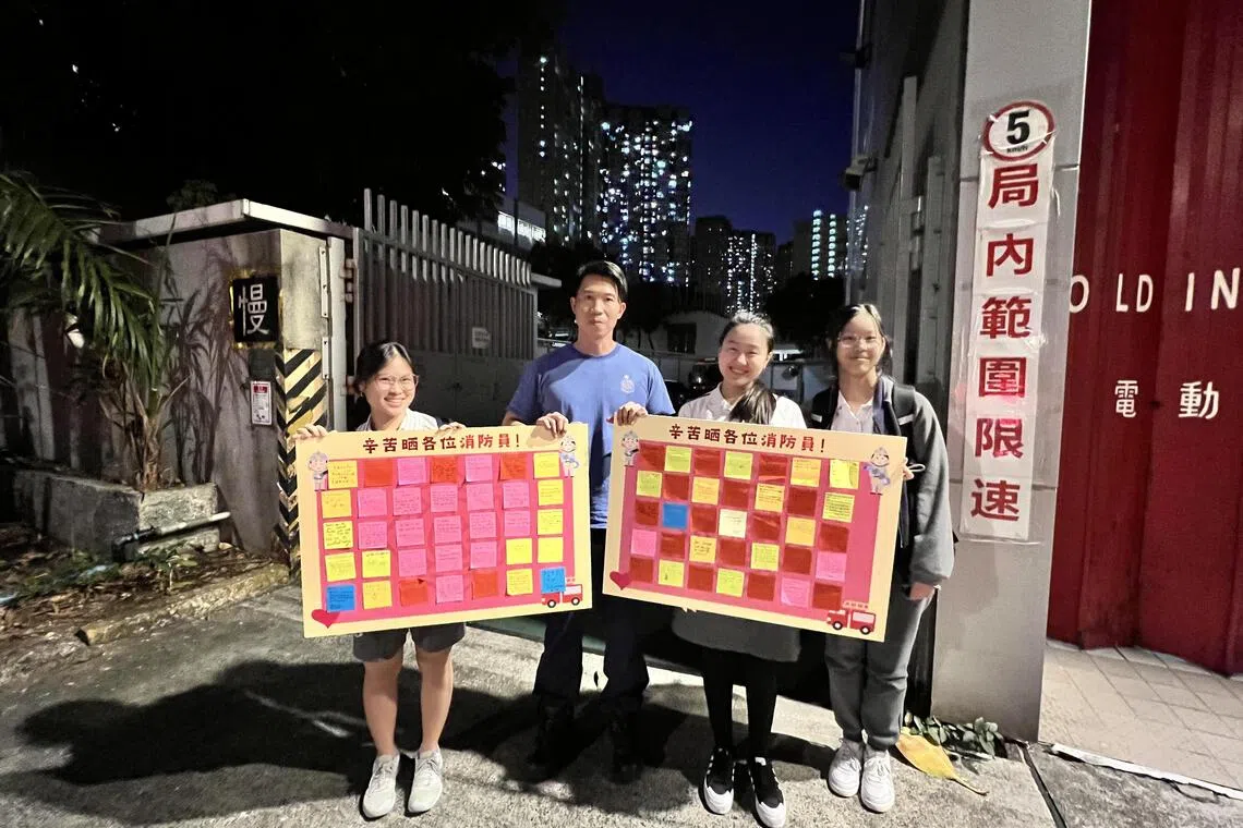 新加坡国际学校（香港）中四学生（左起）刘泳廷、蒋恩萱和薛梓蔚，星期三（12月17日）向大埔消防站的消防员（左二）送上贴有师生和家长感谢信的致谢板。（新加坡国际学校（香港）提供）