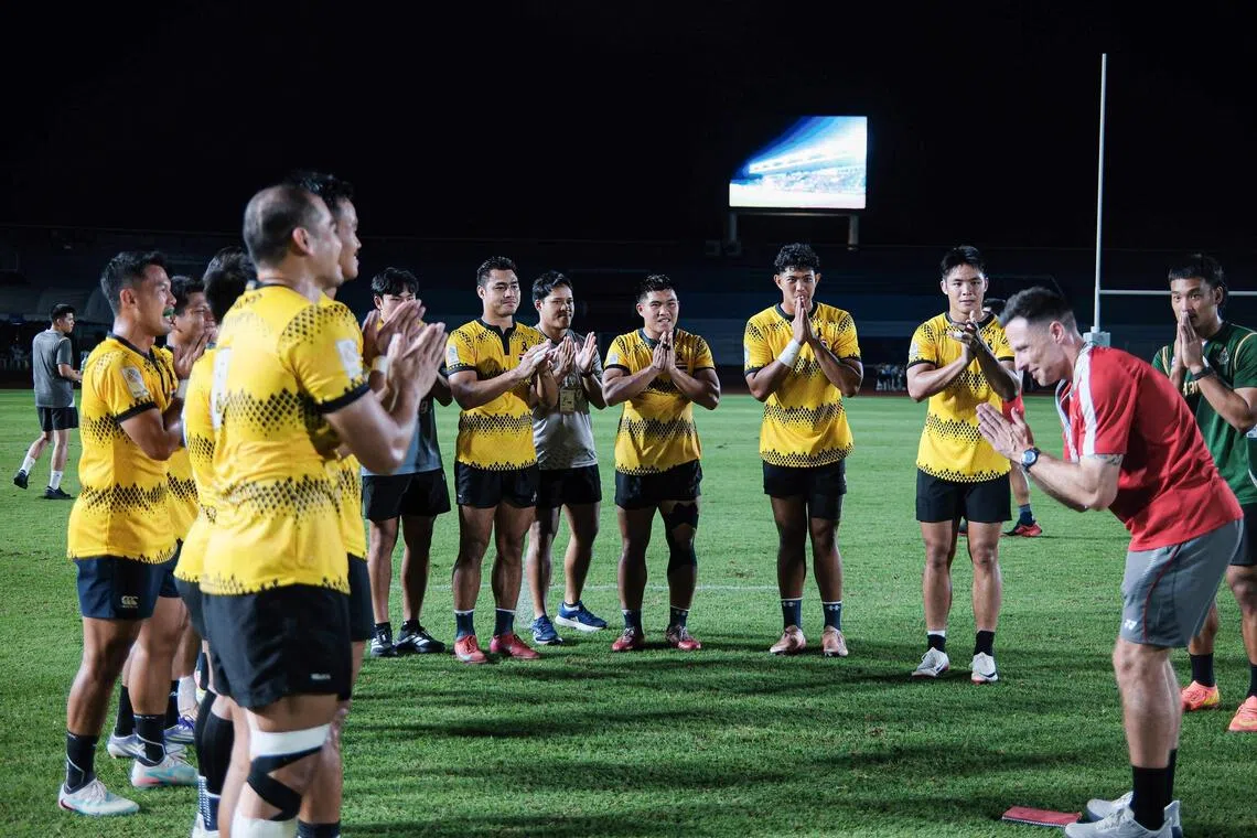 黄色球衣的泰国球员在赛后向蒂杰恩斯（右，红衣）致敬，展现体育精神。（卓舒畅摄）