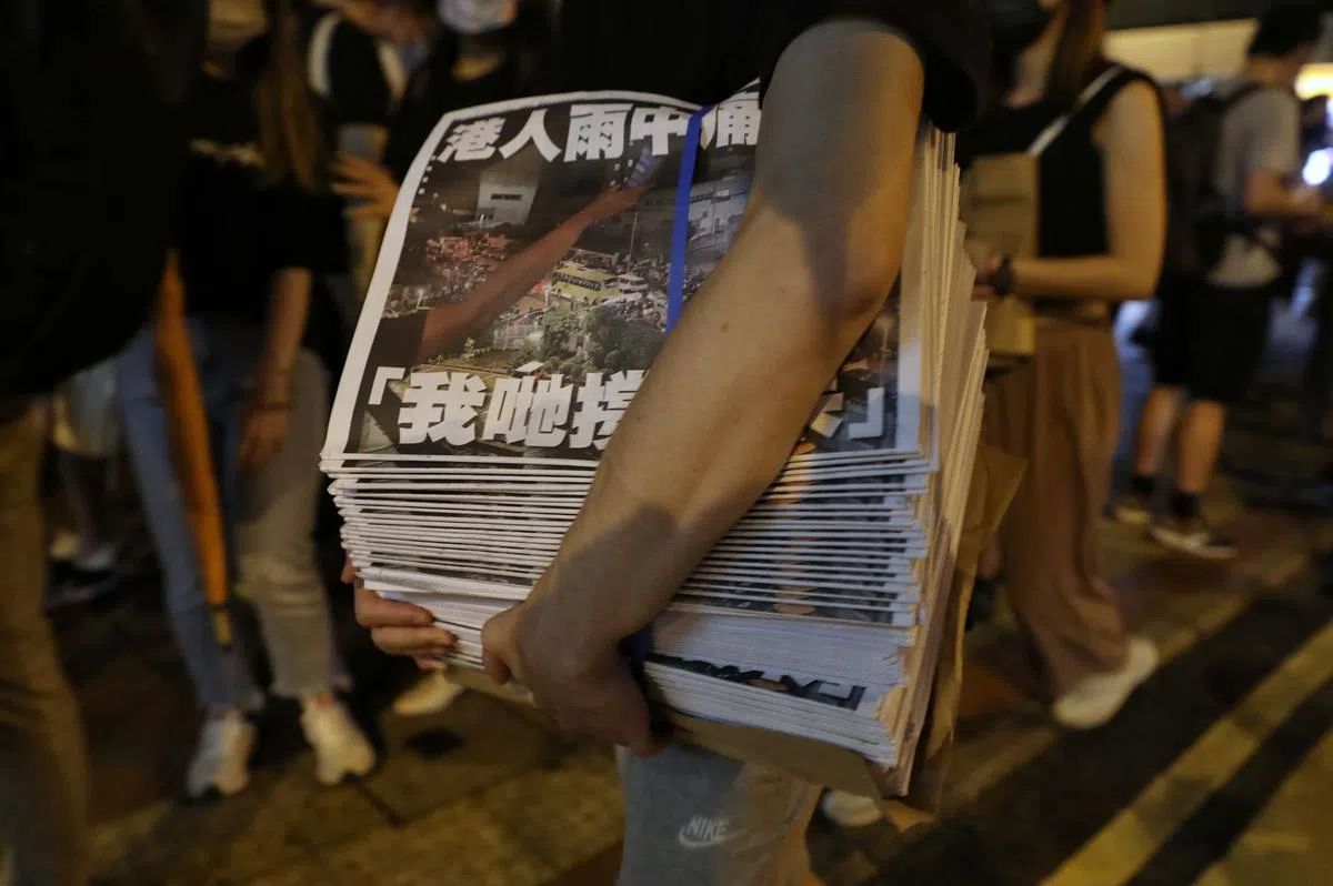一名香港市民今天凌晨在中环的一个报摊购买多份《苹果日报》。（彭博社）