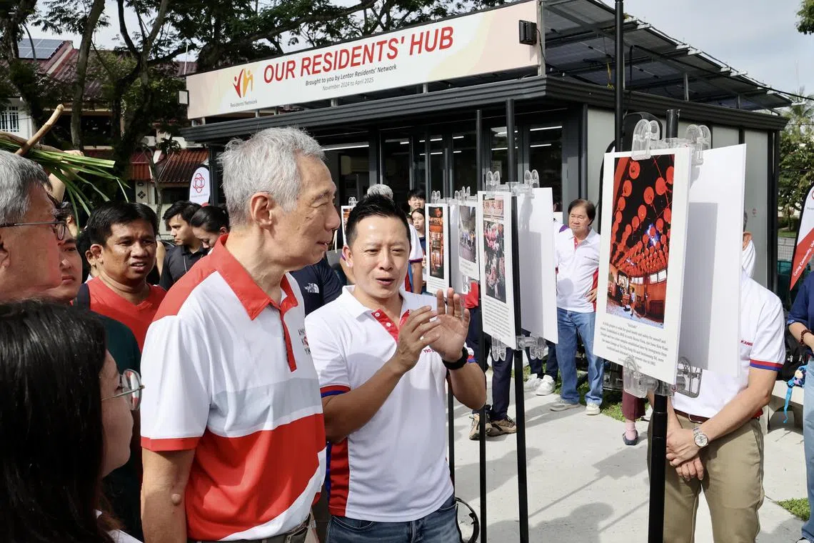 国务资政李显龙（左）和杨厝港区议员叶汉荣星期天（12月1日）出席“杨厝港日”活动，观赏区内摄影比赛展出的得奖作品。（邬福梁摄）