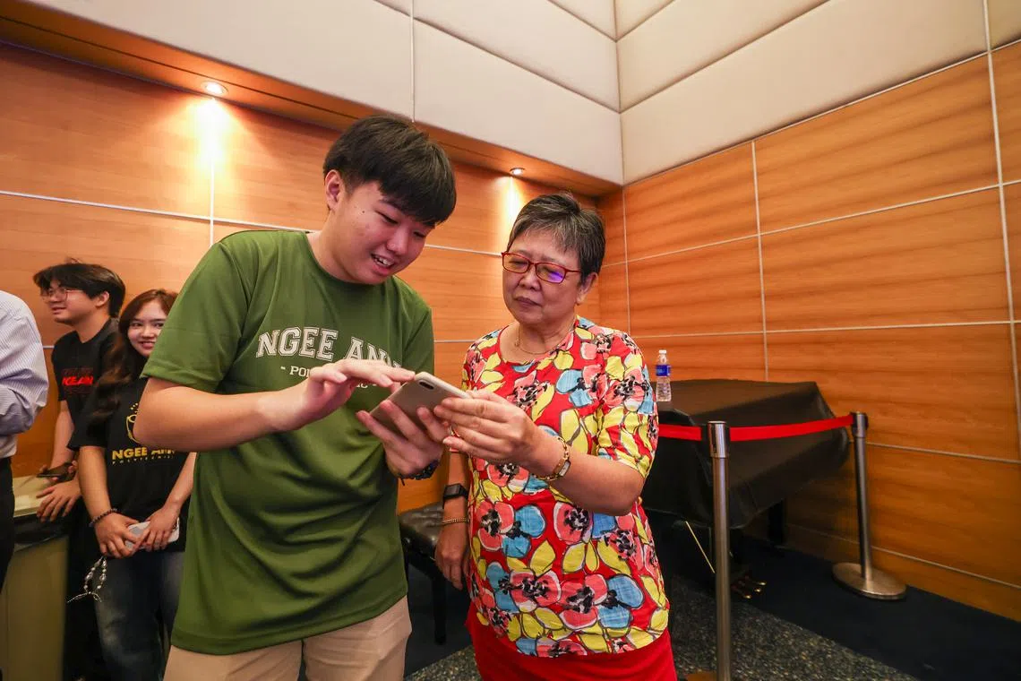 义安理工华文传媒系学生丘瑞安（左）星期三参加数码学堂，从旁为年长者提供技术指导，包括教导参与者黄美兰（右）如何使用手机应用等。（白艳琳摄）