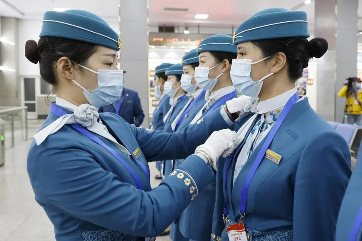 中老铁路全线开通运营，中国列车员上车前整理着装。（中新社）
