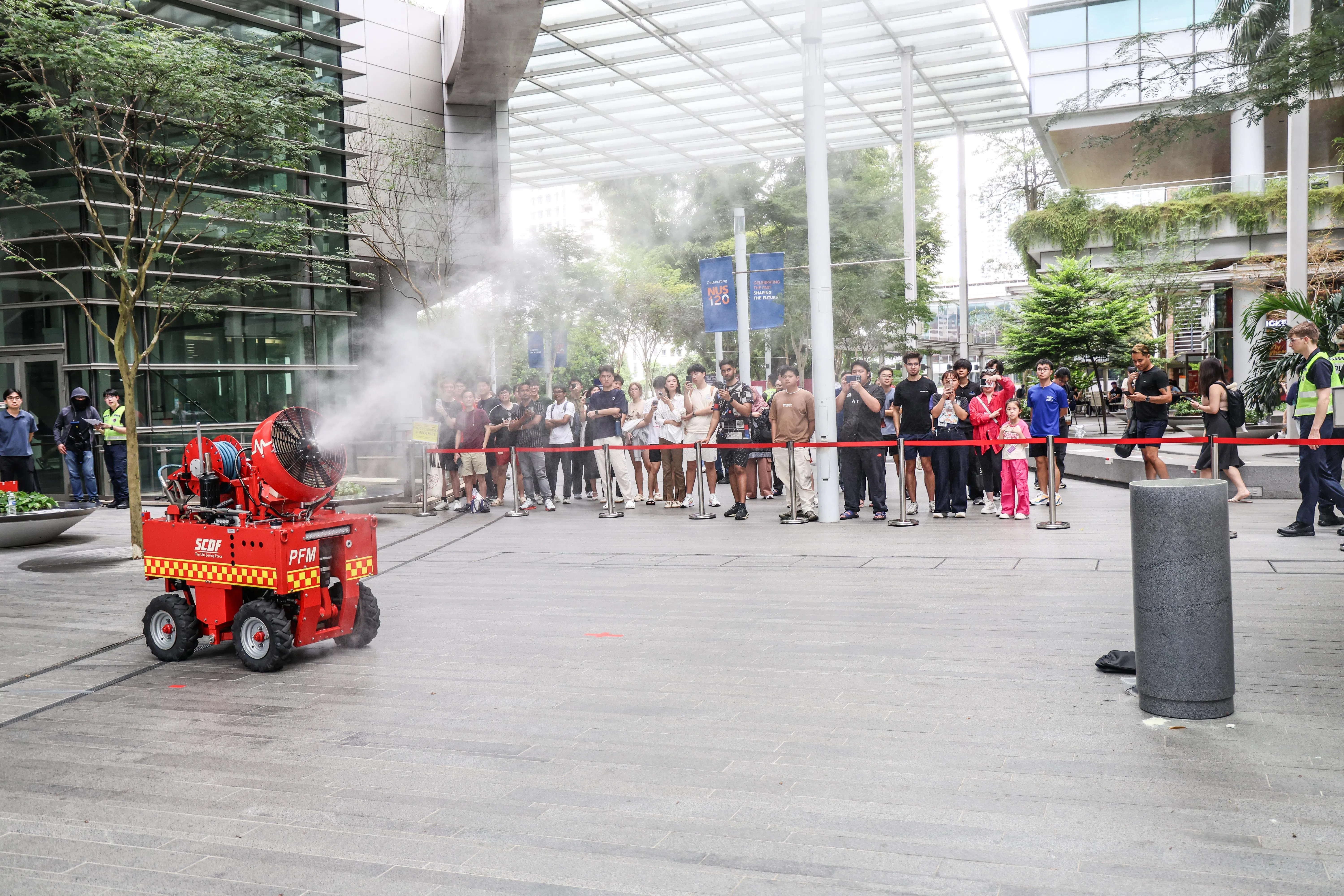 “恐怖分子”引爆垃圾桶里的简易爆炸装置，现场烟雾弥漫。民防部队出动无人驾驶灭火机扑灭火势。（关俊威摄）