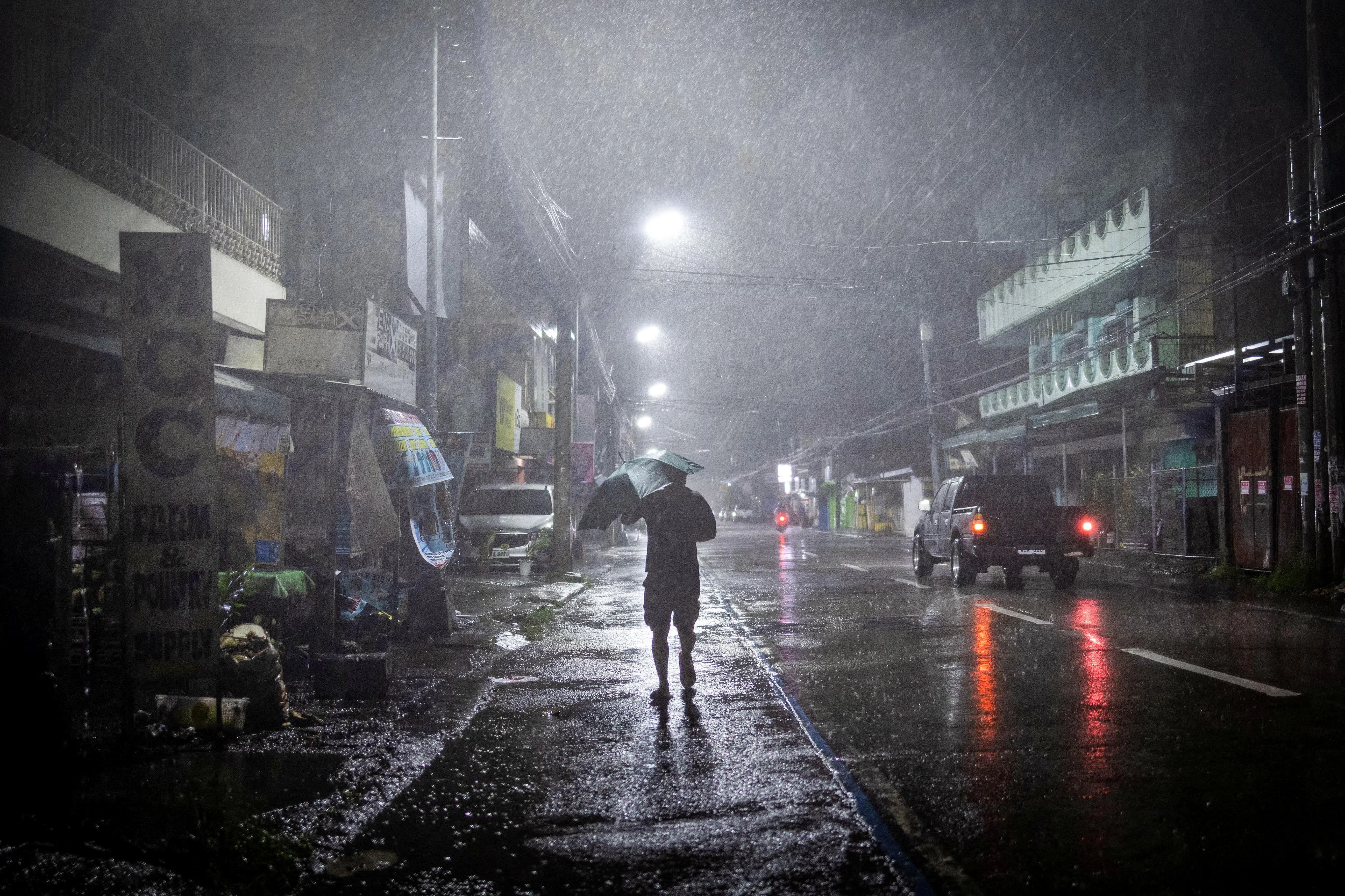 台风凤凰星期天晚登陆菲律宾吕宋岛东部，伊莎贝拉省卡瓦延市一名男子撑伞在滂沱大雨中走回家。（路透社）