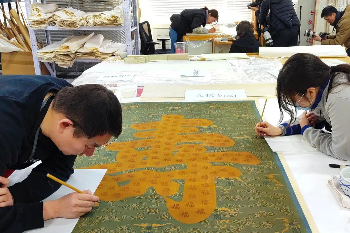 故宫文物修复师正在修补清乾隆时期的缂丝寿字挂屏。挂屏原存于故宫的毓庆宫，为“福”“寿”“绵”“长”四幅挂屏之一，表面有祥云、蝙蝠和寿字纹等寓意吉祥的纹饰。由于修复环节较多，完成整件的修复需要一年左右。（孟丹丹摄）