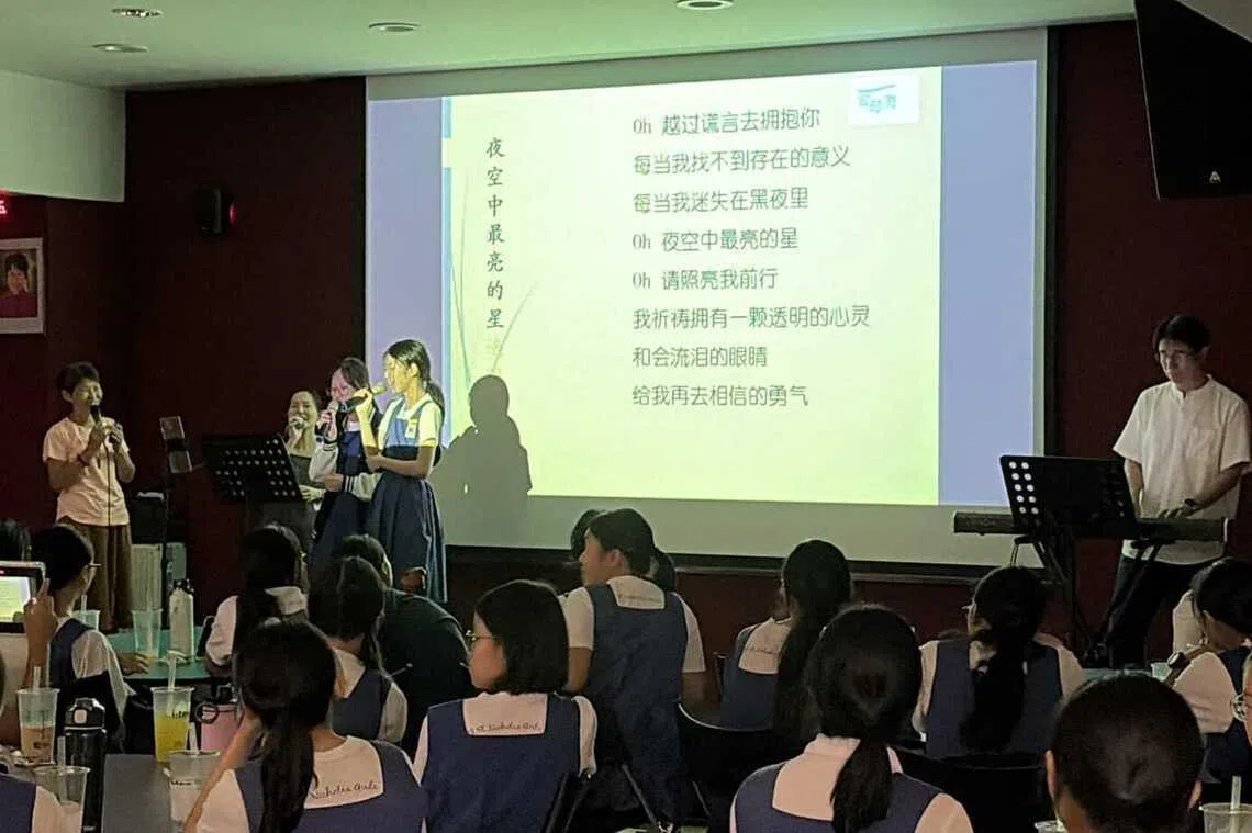 点歌环节中，学生与爱琴海民歌餐厅负责人兼歌手梁定花（左一）一同演唱歌曲《夜空中最亮的星》。（圣尼各拉女校提供）