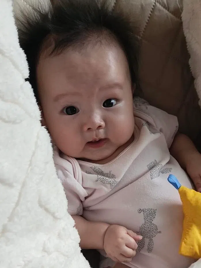 尽管肌肉日益无力，五个月大的小希依旧很阳光，她对世界充满好奇心，会对熟悉的面孔展露笑容，也能认出亲人的声音。（受访者提供）