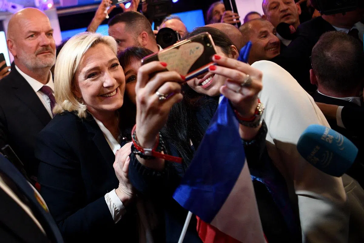 法国总统候选人勒庞在第二轮总统选举出口民调结果出炉后，与支持者合照。（法新社）